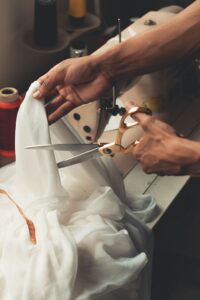 Bilden visar en person som klipper tyg för att skapa något eget och hemsytt med klifria tyger på metervara online